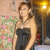 A pixelated image of a woman in a black strapless dress standing near a floral arrangement and a bright light source.