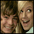 Two people in close proximity, one with dark hair and the other with light hair, both smiling against a white background with pink text reading 'Friends Forever' and decorative elements.