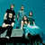 Four figures stand on a rocky outcrop against a teal background, with text reading "FLYLEAF!" and "63" on a black to the right