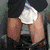 A person in a dark suit lifts their skirt to reveal white underwear, then lowers the skirt while holding a red heart symbol.
