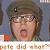 Pixelated close-up of a person with short brown hair wearing glasses, mouth open in a shout or yell, against a blurred background with a red and green object on the left.