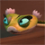 Pixelated cartoon animal with large blue eyes, pink ears, and a green-yellow body lying on a brown surface.