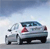 Pixelated image of a silver sedan with red taillights on a light gray road under a blue sky with white clouds.