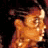 Pixelated static image of a stylized orange-yellow figure with dark hair against a black background, featuring dithering and color blending effects.