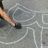 A pixelated static image shows a partial figure with light skin and dark hair against a gray background with white lines.