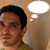 Pixelated portrait of a person with dark hair wearing a green shirt, set against a light brown background with a white thought bubble.