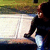 A person in dark clothing and light pants sits on a bench, with background elements shifting across frames.