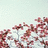 Pixelated image of pink and red floral shapes against a light blue background with scattered white pixels.
