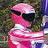 Pixelated figure in pink outfit with dark sunglasses and light-colored headwear against blurred green and blue background.