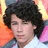 Pixelated portrait of a person with dark curly hair against a multicolored background featuring orange, pink, and yellow tones.
