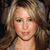 Pixelated close-up of a person with light brown wavy hair, fair skin, and visible facial features including eyes, nose, and lips.