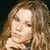 A 50x50 pixel animated contact sheet showing two frames of a woman with long wavy blonde hair in a light-colored top, displayed side-by-side on a dark background.