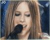 Animated sequence of a woman with long brown hair singing into a black microphone against blue and red stage lighting.