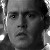 Black-and-white pixelated portrait of a person with short hair, neutral expression, and visible ear, cropped to show upper face and shoulder.