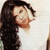 Pixelated close-up of a person with long dark hair wearing a white top, head turned right, against light background.