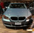 Static pixelated image of a silver sedan viewed from the front, positioned on a light brown surface with dark background elements.