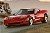 Pixelated static image of a red convertible car with black top on a road, surrounded by blurred background elements including trees and sky.