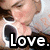 A person in a white shirt with dark hair holds their hand near their face, displaying the word 'Love.' on black text overlay.