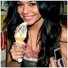 A person with long dark hair holds a cone-shaped ice cream with colorful sprinkles and a pink scoop, smiling at the camera.