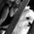 Black-and-white pixelated image of a stylized figure with a large head, dark hair, and a single visible eye, set against a gradient background.