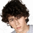 Pixelated close-up of a person with dark curly hair, light skin tone, and neutral expression against white background.
