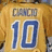 Yellow sports jersey with blue number 10 and name 'GANDI' on back, set against solid blue background with yellow text reading 'my friend', 'my team mate', and 'my brother'.