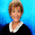 Static pixelated image of a person with short brown hair wearing a black top with white collar against blue gradient background.