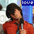 A person in a red jacket holding a microphone with 'love' text above, shown in two side-by-side frames where the head position shifts slightly.