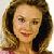 Static pixelated image of a person with light brown hair styled in loose waves, wearing dark earrings and a pink garment visible at the bottom edge.