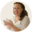 Pixelated circular image of a person with long dark hair wearing a white top, hands raised in a clapping gesture against a light background.