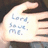 A hand holds a white card with blue text reading 'Long Love Me.' The background is dark and indistinct.