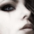 Close-up of a person's face showing eye, nose, and mouth with dark hair against light background.