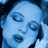 Pixelated blue-toned static image of a stylized face with closed eyes and visible facial features including eyebrows, nose, lips, and hair against dark background elements.