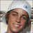 Pixelated portrait of a smiling person wearing a white beanie with blue logo on left side, set against solid dark purple background with pink text elements.