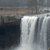 A static pixelated image shows a waterfall with multiple streams flowing downward against a dark rocky background under a muted sky.