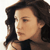 Pixelated close-up of a person with dark hair wearing a dark top, viewed from the side against a light background.