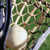 A static image of a golden helmet on green grass with black metal bars, viewed from above.