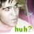 Pixelated close-up of a person's face with closed eyes and light skin, overlaid by green text reading 'huh?' on a pastel background.
