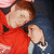Two figures in red and blue clothing embrace, with one figure's head resting on the other's shoulder