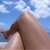 A pixelated image shows a person's legs and feet against a blue sky with white clouds, with the lower legs and feet positioned in the foreground.