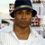A pixelated static image shows a person wearing a dark blue cap with a light band, a white shirt, and a brown beard, set against a light background with blurred shapes.