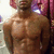 Pixelated static image of a shirtless figure with brown skin tone, visible chest and abdominal muscles, and a small red mark on the chest.