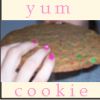 A static image shows a hand with pink nail polish holding a cookie with green and red sprinkles, with 'yum' text above and 'cookie' text below.