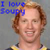 Two side-by-side pixelated images of a person with curly red hair wearing a dark shirt with yellow and white trim, each with text above the head.