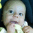 Pixelated close-up of a child's face with light hair, blue eyes, and a neutral expression against dark background.