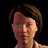 Pixelated close-up of a person with short brown hair against black background, wearing dark top.