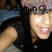 Pixelated image of a person with light skin and brown hair wearing dark clothing, holding an object near their face against a blurred background.
