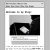 Black and white pixelated image showing a dark shape with a bright circular element against a light background, framed by blurred interface elements.