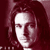 Pixelated static image of a person's face with long dark hair against a maroon background, rendered in low-resolution 256x256 pixels.