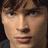 Pixelated close-up of a person's face with brown hair, light skin tone, and neutral expression against dark background.